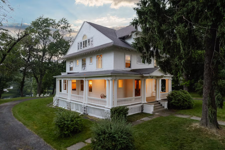 Folk Victorian home at twilight with wraparound porch — Wixom's older housing stock